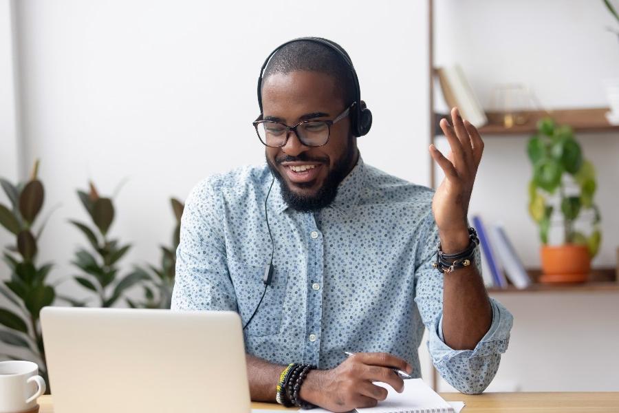 Male student sitting infront of laptop smiling.